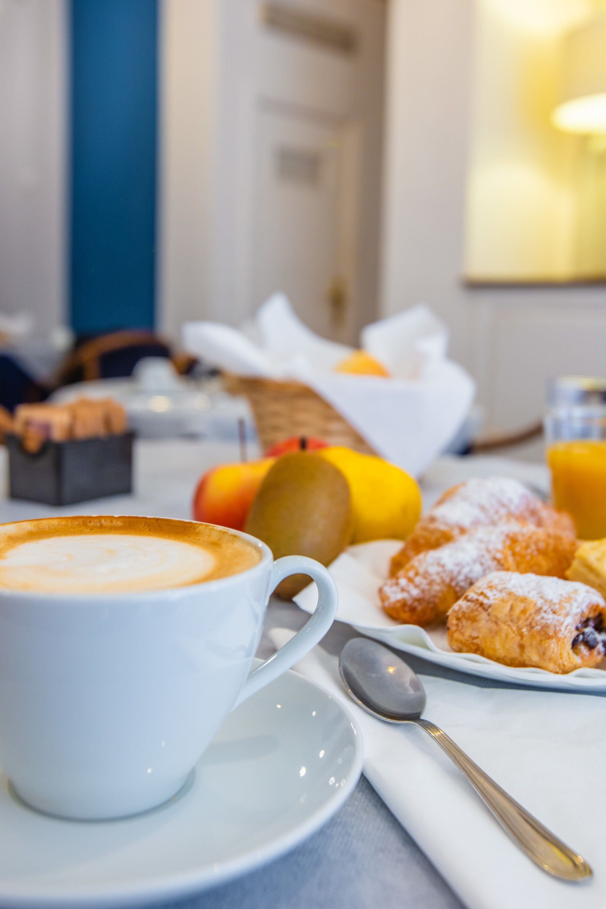 Ein Frühstückstisch mit einer Kaffeetasse, Gebäck und einer Obstschale.