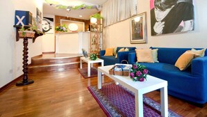 Una sala de estar con un sofá azul, una mesa de centro blanca y un tapete estampado.