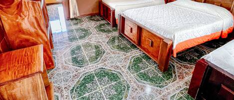 A room with wooden walls and a patterned floor. There are two beds with white bedding and a bench.