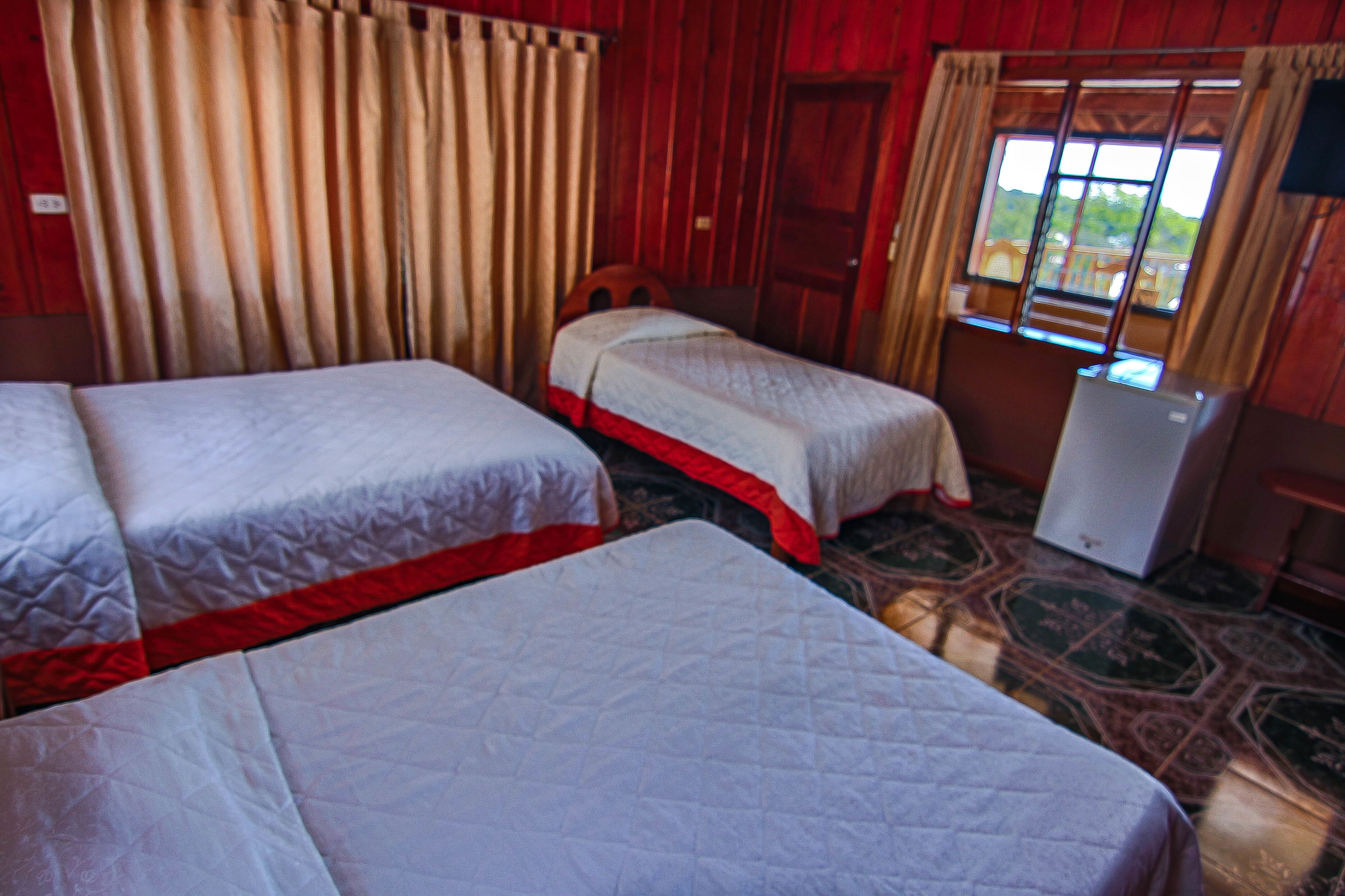 Een kamer met twee bedden, een tafeltje en een raam met gordijnen.