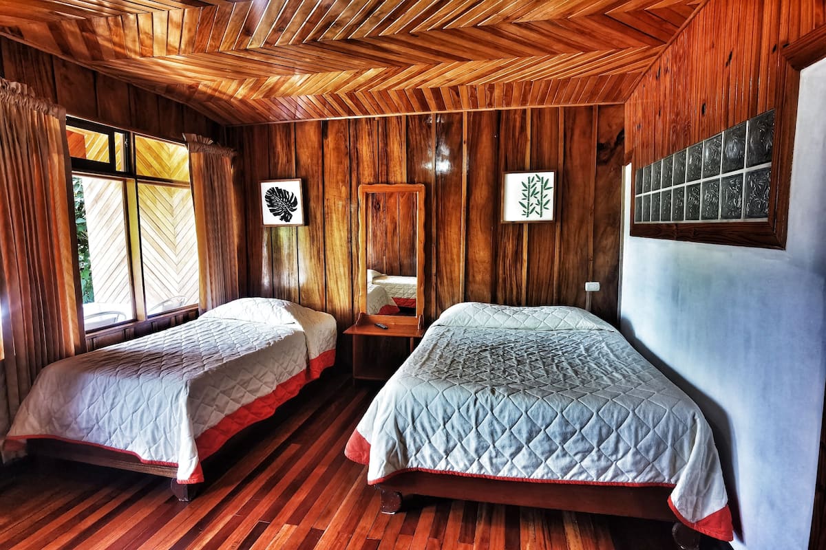 Una habitación con dos camas, paredes de madera y techo de madera.