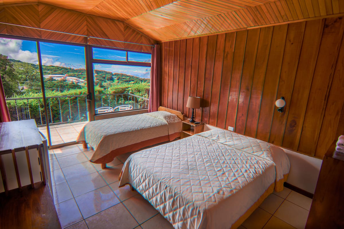 Un dormitorio con dos camas, un escritorio y un balcón con vistas panorámicas.