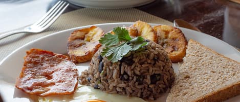 A plate with fried rice, a fried egg, toast, and a piece of ham.