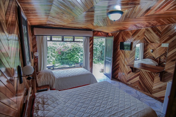 Una habitación con paneles de madera, dos camas, un ventanal y un televisor.
