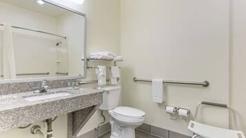 Baño con lavamanos de granito, inodoro blanco, toallero y barra de apoyo.