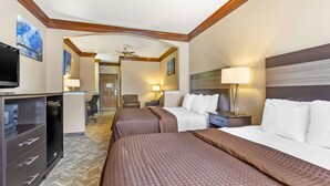 A hotel room with two beds, a desk with a TV, and a seating area with a chair and lamp. - Best Western Fort Worth Inn & Suites (Fort Worth)