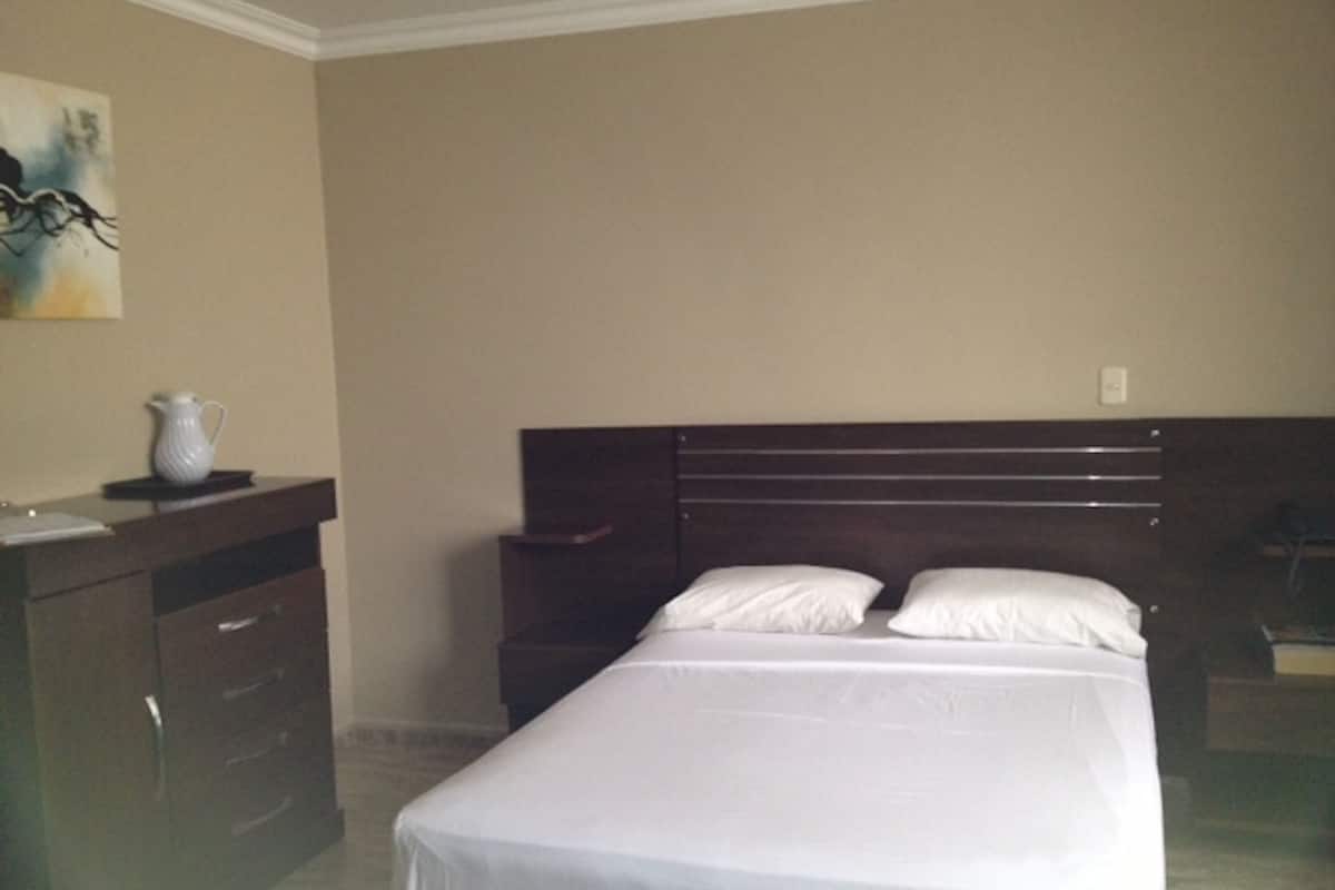 A bedroom with a bed, a dresser, and a nightstand.