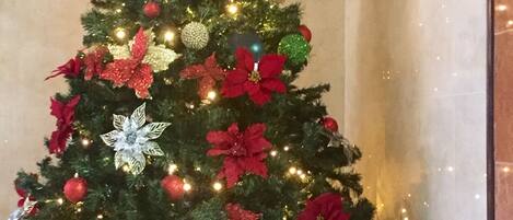 A Christmas tree decorated with red and silver ornaments, lights, and poinsettias.
