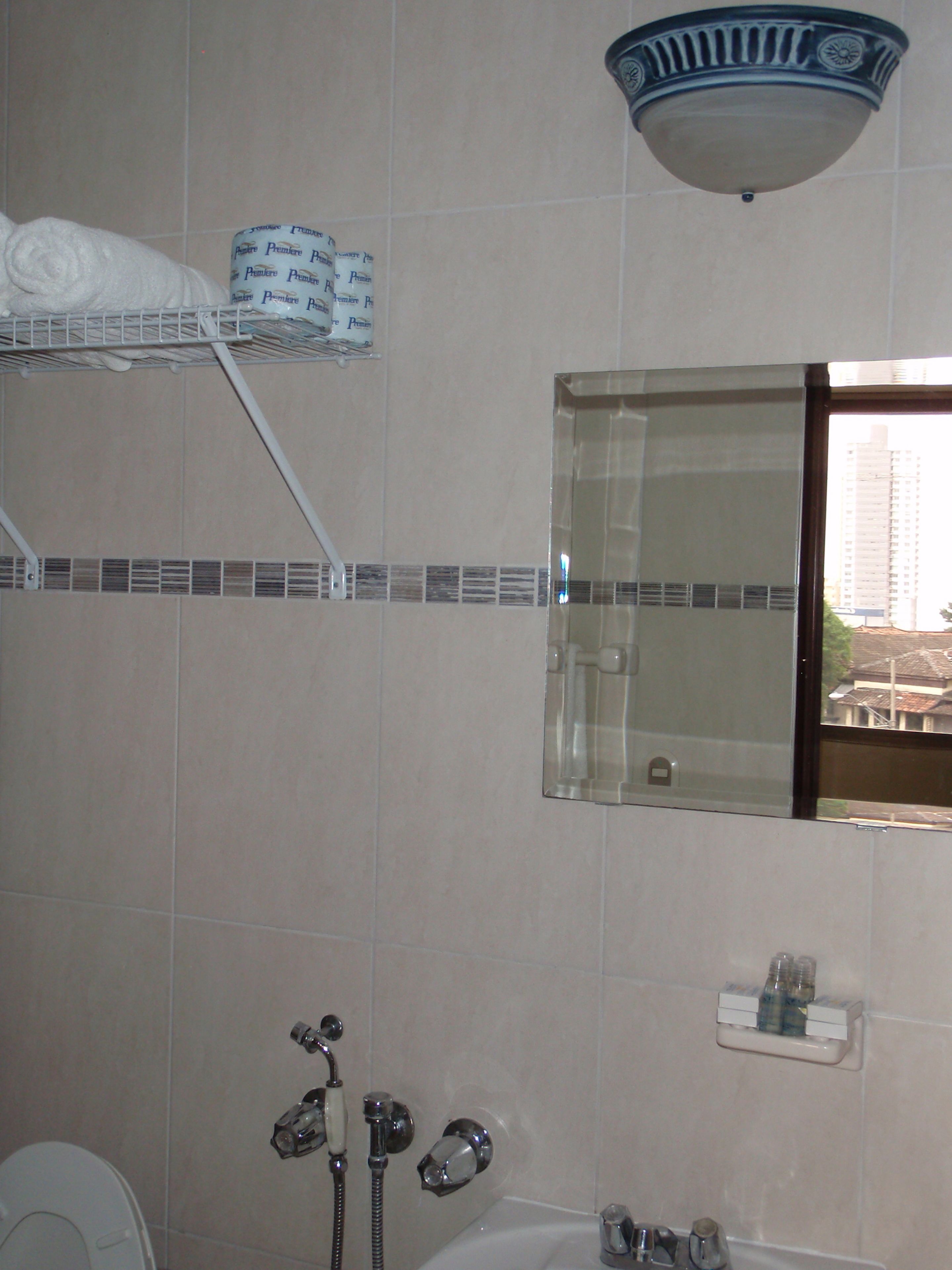 Un baño con ducha, inodoro, lavabo, espejo y toallero.