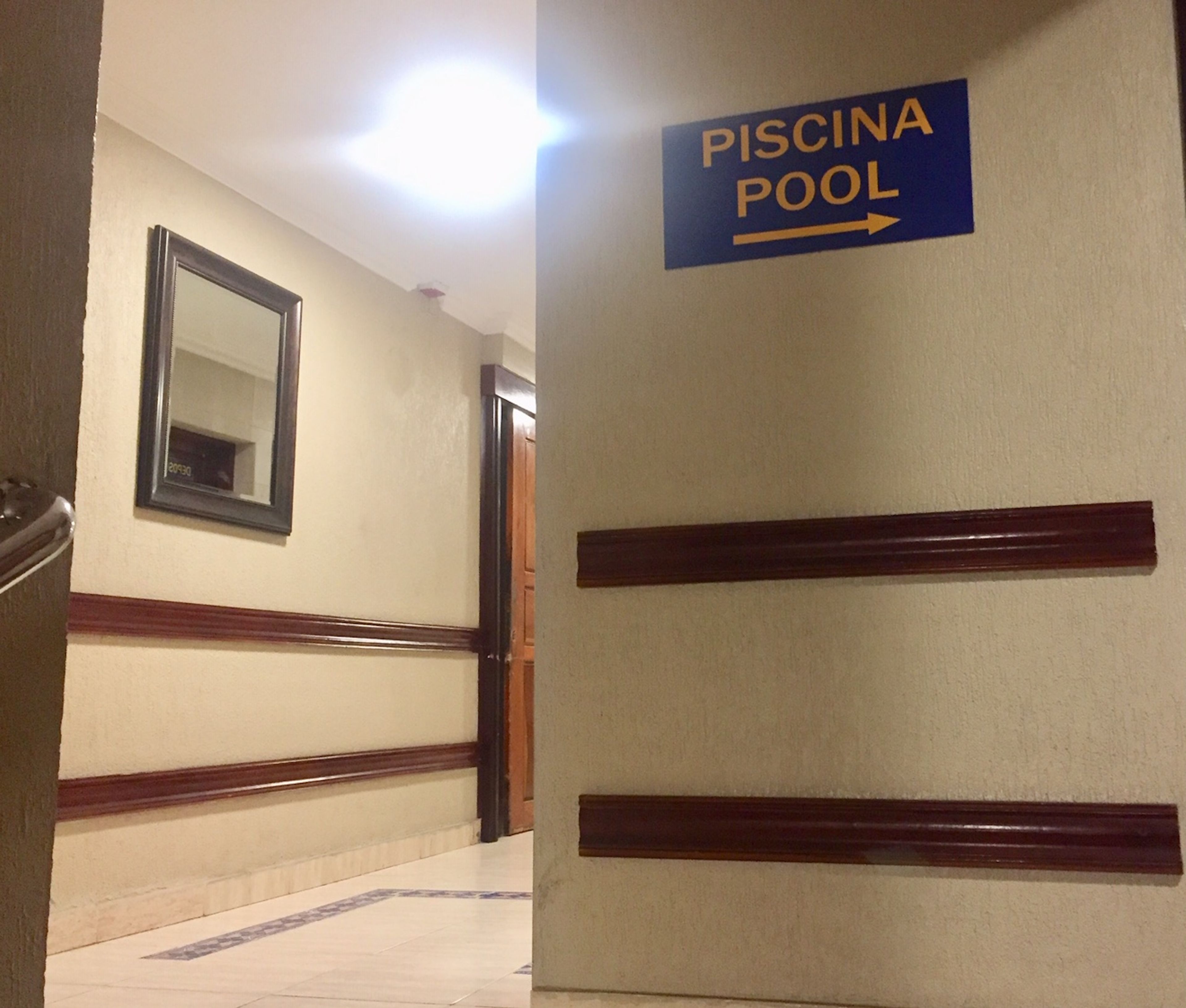 Een gang met een bord dat de weg naar het Piscina Pool aangeeft.
