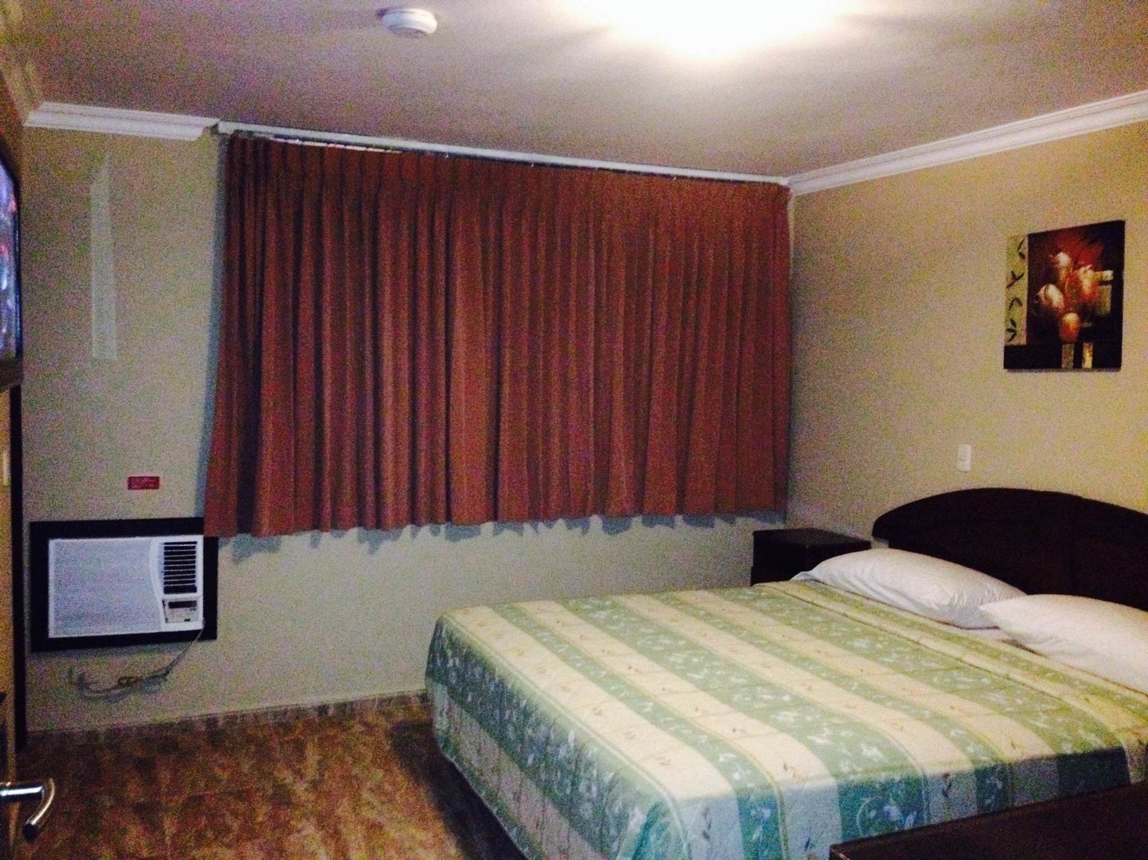 Ein Schlafzimmer mit Bett, einem fensterbepften Fenster, einer Wand-Klimaanlage und einem Gemälde.
