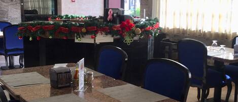 Un restaurante con una mesa larga, sillas azules y una decoración navideña.