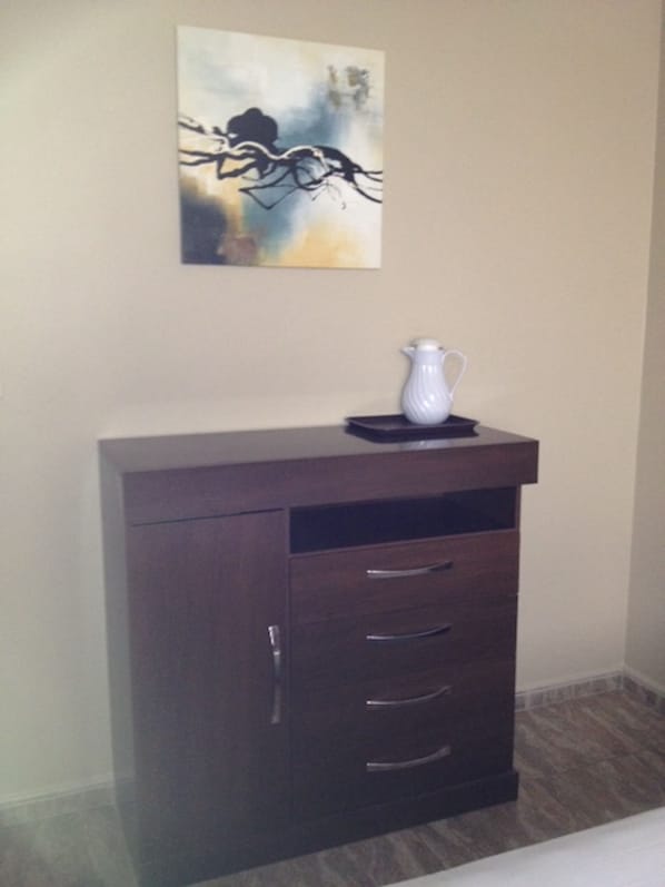 A dark wooden cabinet with three drawers and a white pitcher on top. - Euro Hotel (Panama City)
