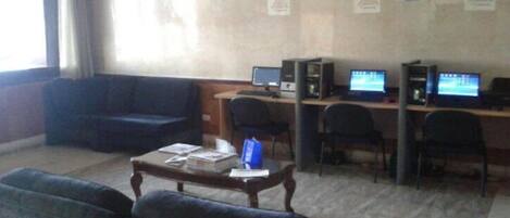 Una habitación con un sofá, una mesita de centro y un escritorio con computadoras.