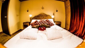Una cama con sábanas blancas, un cabecero de madera y dos mesitas de noche con lámparas.