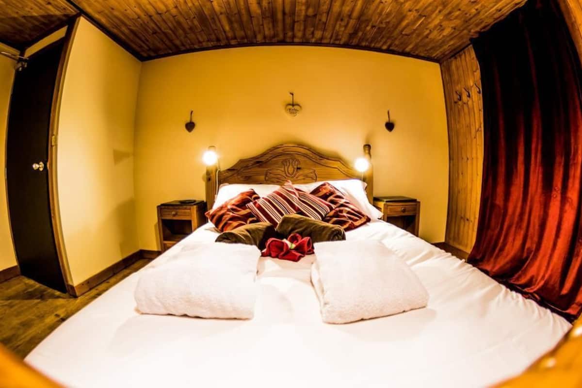 A bed with white linens, a wooden headboard, and two bedside tables with lamps.