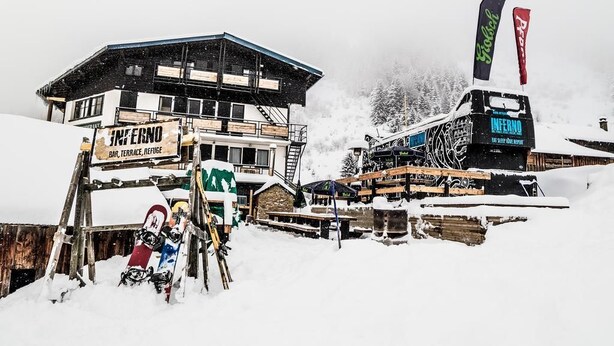 Un edificio cubierto de nieve con un letrero que dice 'INFERNO BAR, TERRACE, REFUGE'.