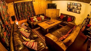Una sala de estar acogedora con sofás de cuero, una mesa de centro de madera y una estantería.