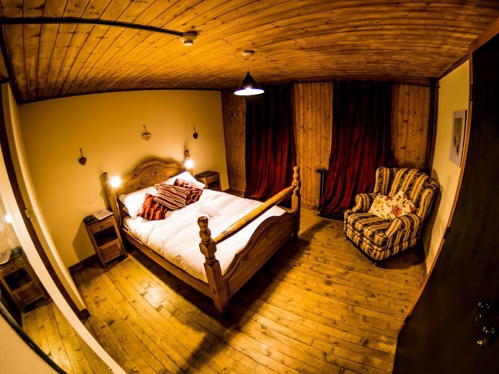 Una habitación con una cama de madera, una silla y techo de madera.
