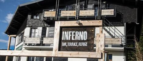 Un edificio de varios pisos con un letrero llamativo que dice "INFERNO BAR, TERRACE, REFUGE".