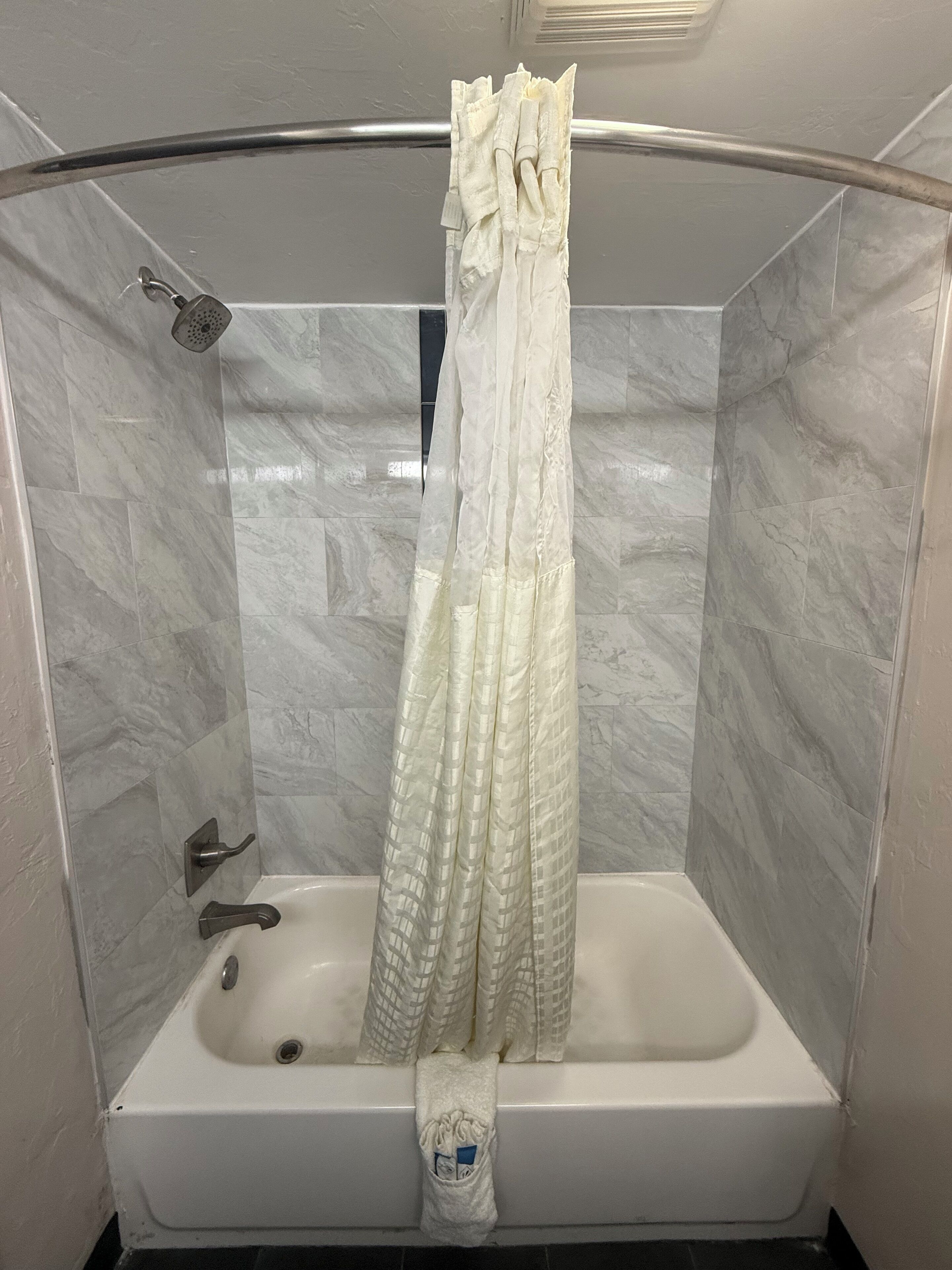 A modern bathroom with a glass-enclosed shower, a white bathtub, and marble tiles.
