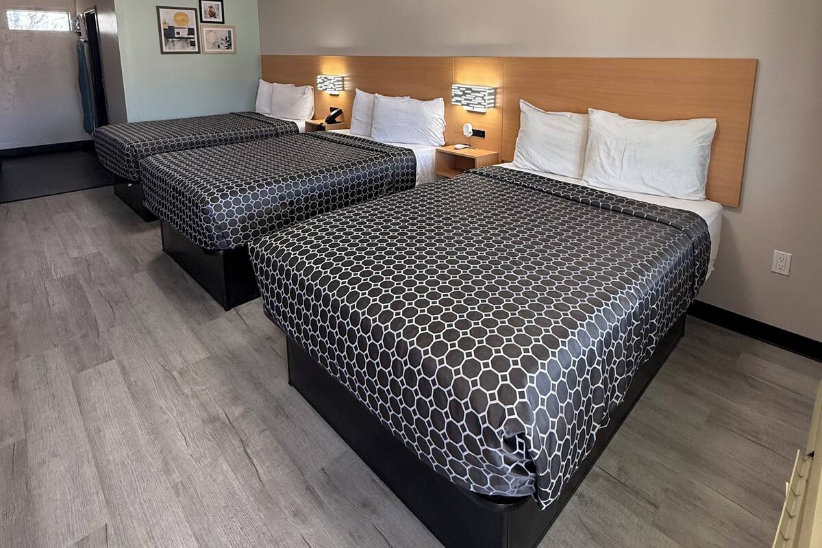 A hotel room with two beds, a wooden headboard, wall-mounted lights, and a ceiling light.