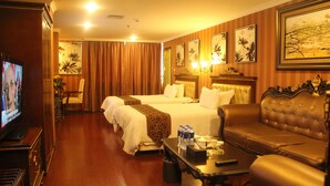 Habitación de hotel con dos camas, un sofá, un televisor y obras de arte en las paredes.
