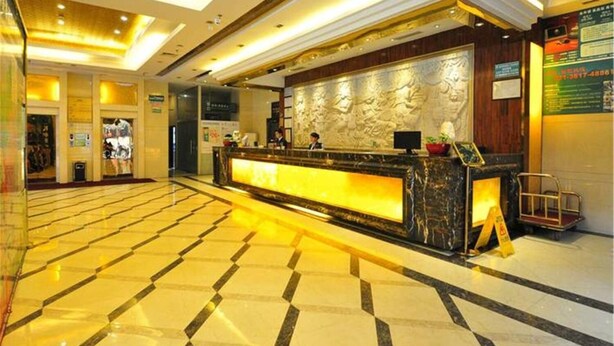 Zona de recepción de hotel con suelo de mármol, mostrador y una pared con diseño decorativo.