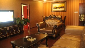 Una sala de estar con un sofá de cuero, un sillón tapizado, una mesa de centro, un televisor y una planta en maceta.