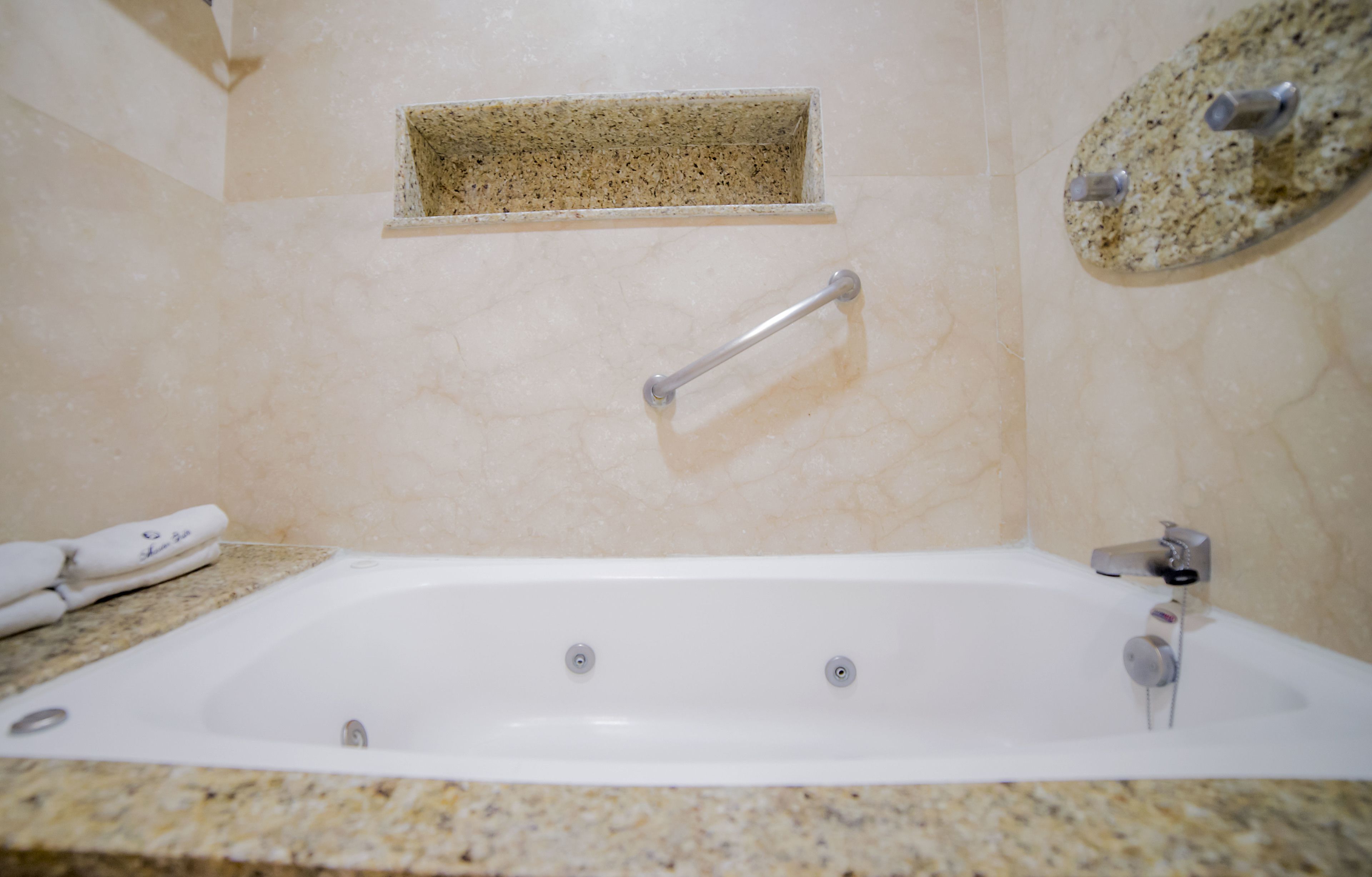 Un baño con una bañera, un perchero y un pequeño estante sobre la bañera.