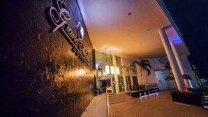 A hotel entrance with a modern design, featuring a prominent sign, a staircase leading to the lobby, and a well-lit interior.