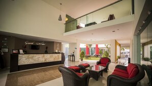 A hotel lobby with a reception desk, seating area, and a glass railing overlooking the interior.