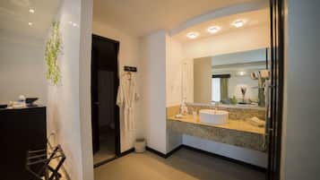 Un baño moderno con encimera de granito, un espejo grande y un lavabo blanco.