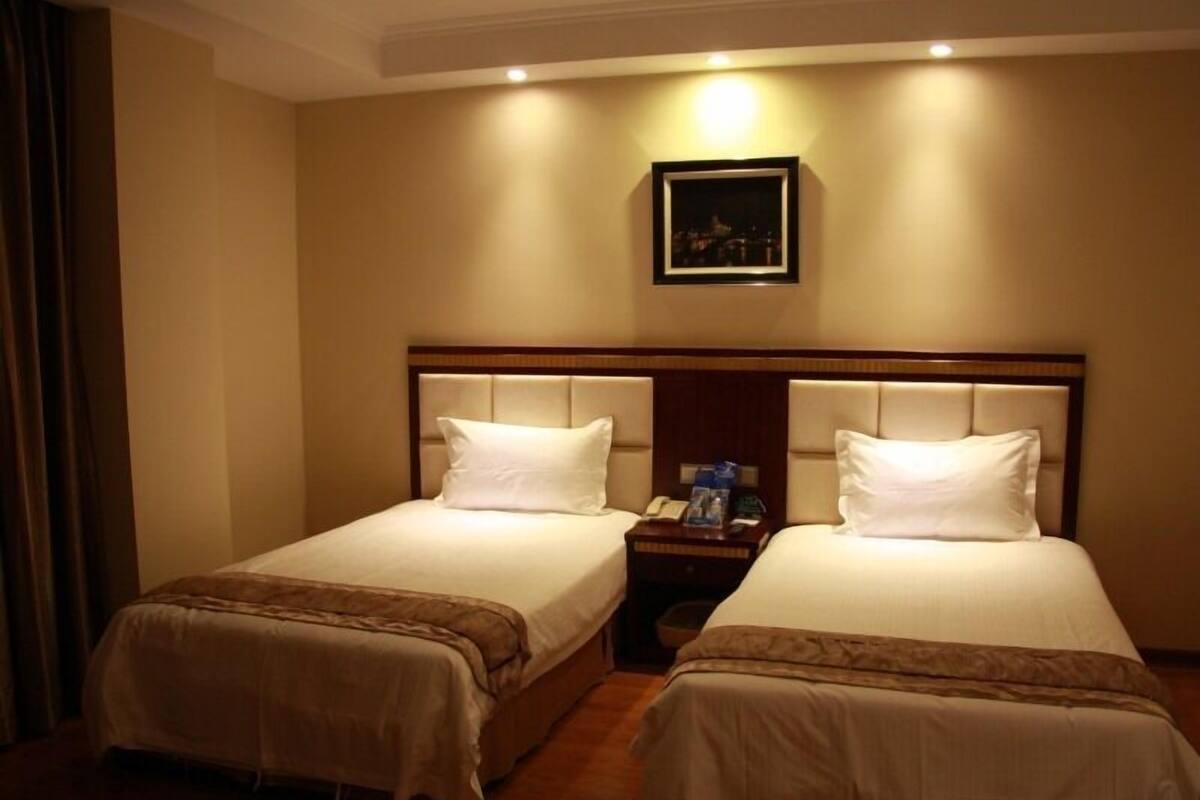Una habitación de hotel con dos camas, una mesita de noche y un cuadro en la pared.
