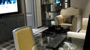 A modern living room with a glass coffee table, a black keyboard, a beige sofa, and a television mounted on the wall. - GreenTree Inn Shantou Chengjiang Road Business Hotel (Shantou)