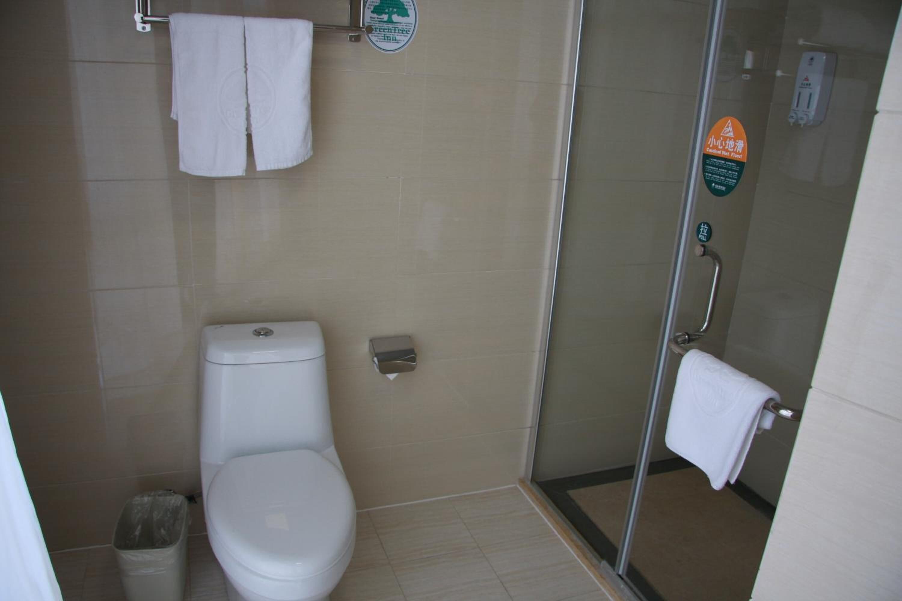 A bathroom with a toilet, a glass shower enclosure, and a hand dryer.