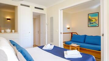 Une chambre d’hôtel avec un lit, un canapé, une petite table et un luminaire fixé au mur.