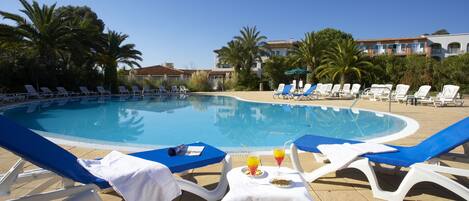 A poolside area with lounge chairs and a table with drinks.