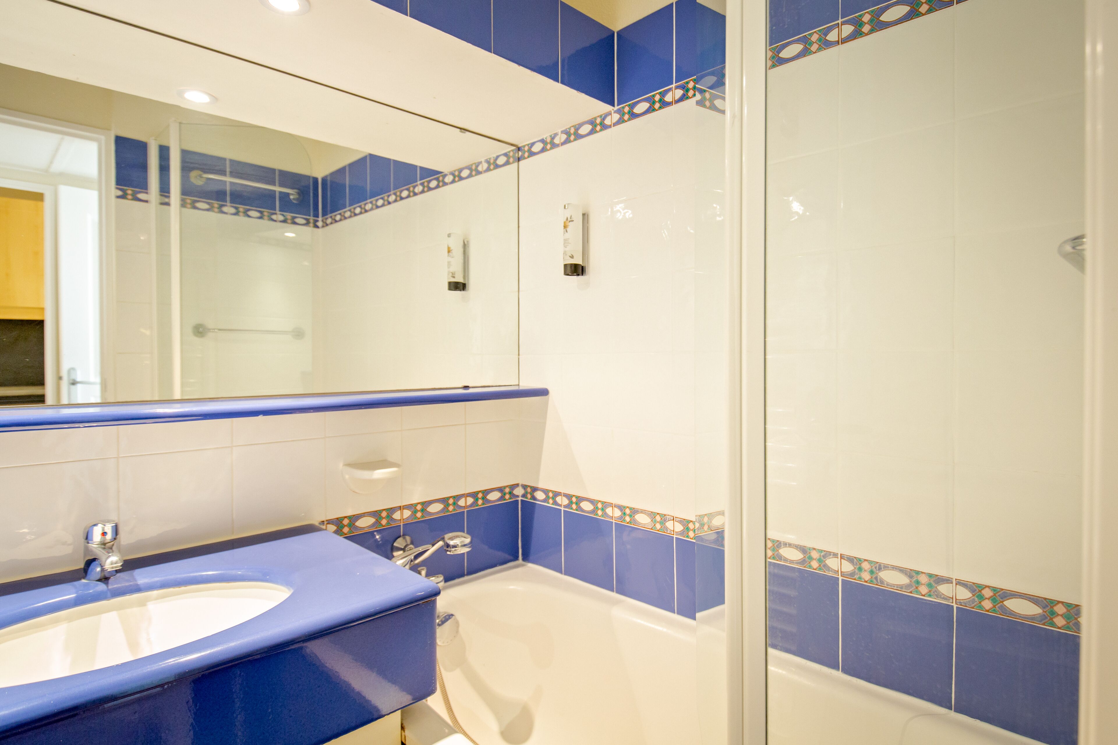 A bathroom with a sink, bathtub, and a glass shower enclosure.