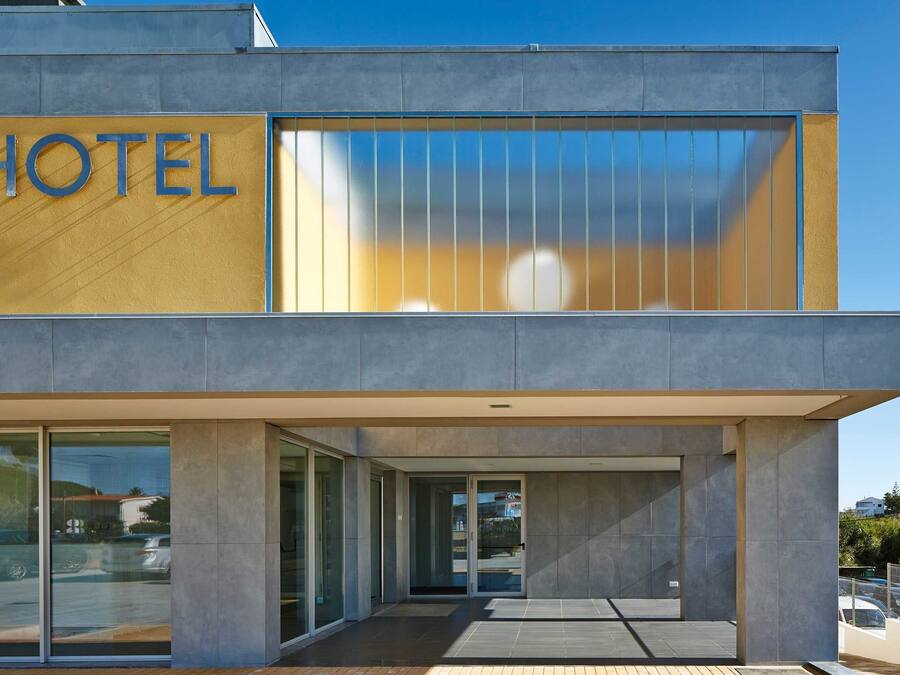 A modern hotel with a prominent "HOTEL" sign, large glass windows, and a clean, contemporary design.