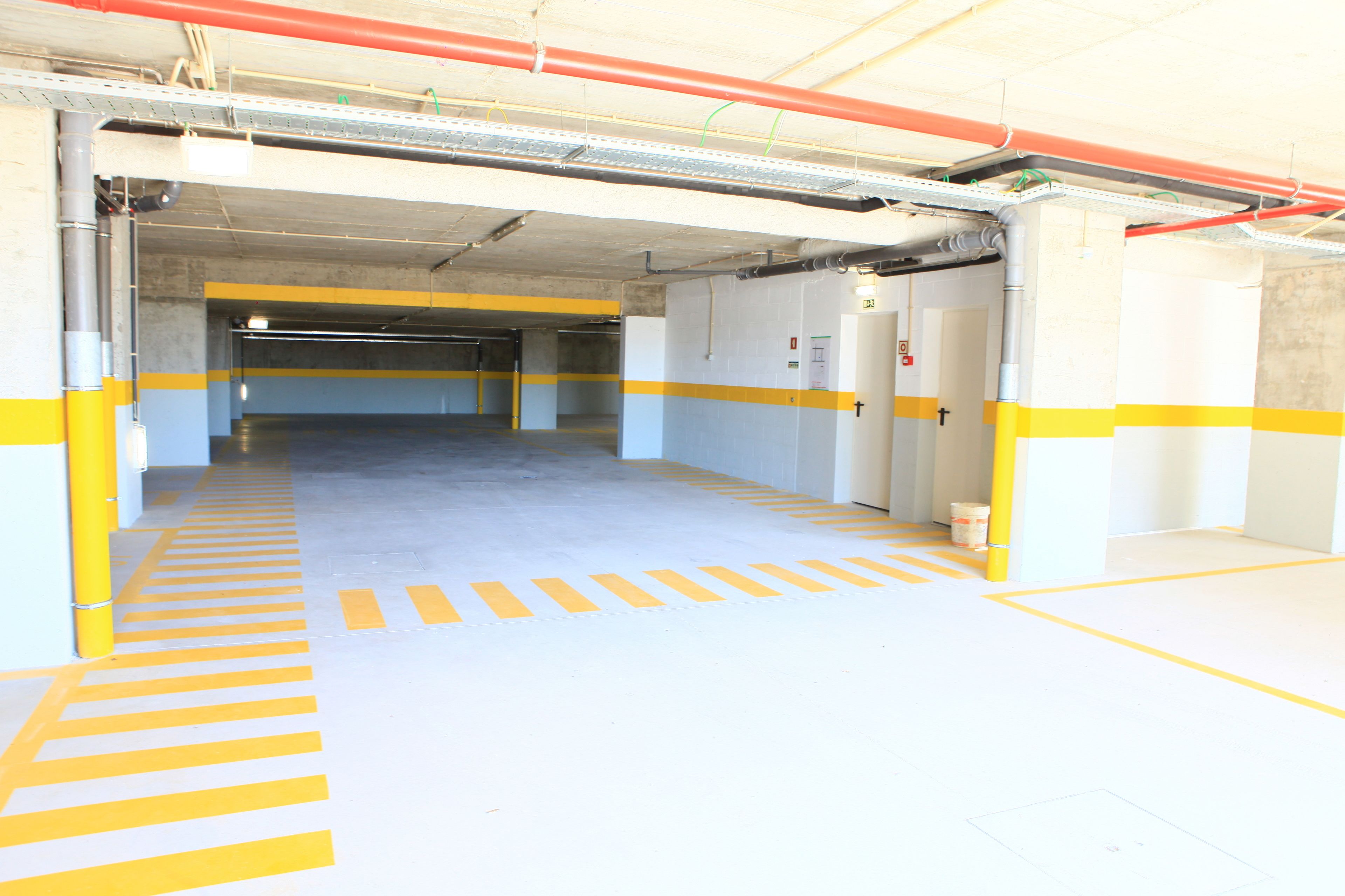 An empty parking garage with yellow and white painted lines and walls.