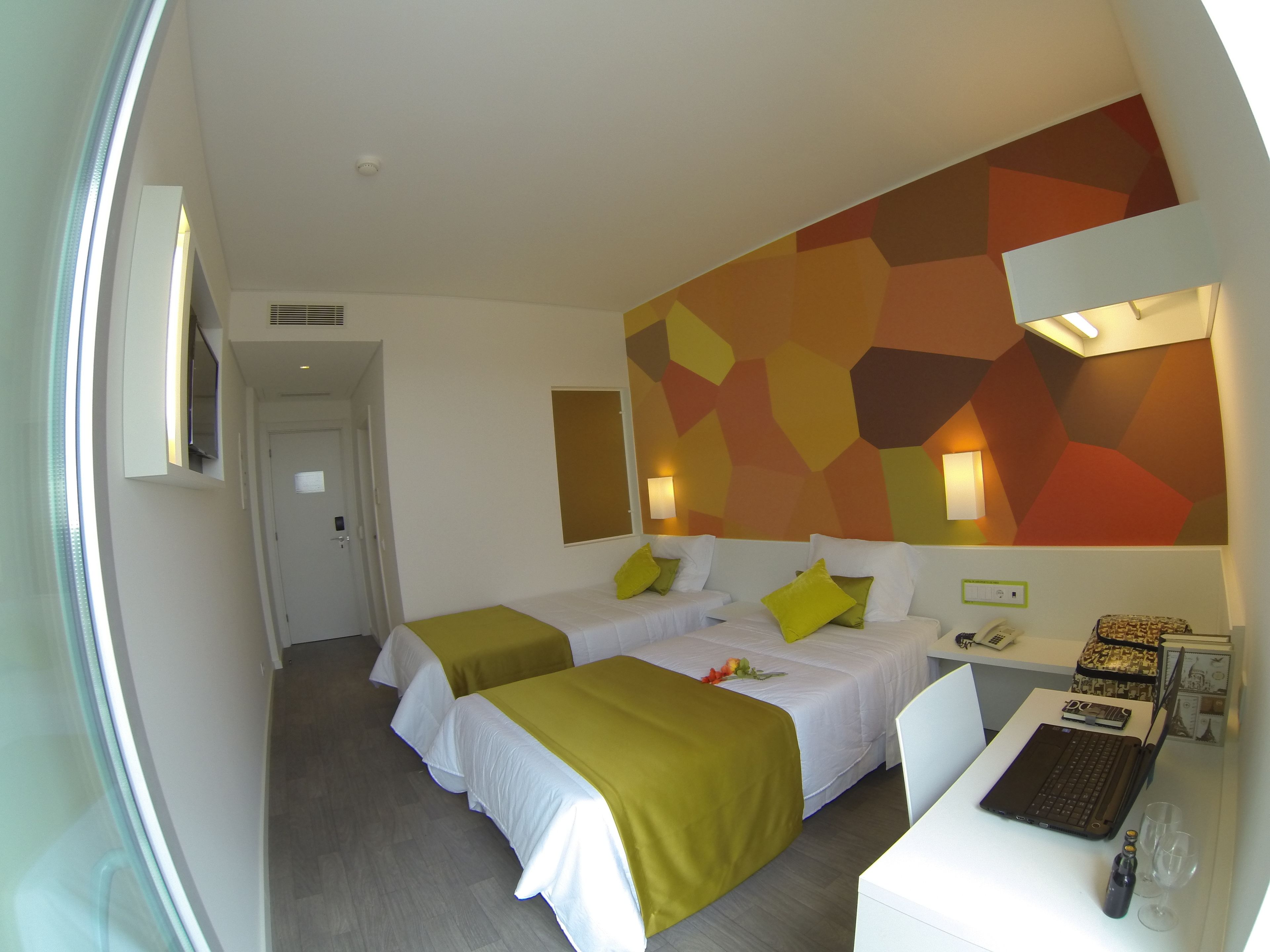 Habitación de hotel con dos camas, un escritorio y una computadora. Se ve una ventana al lado izquierdo.
