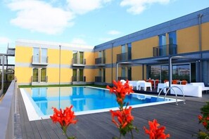 A modern hotel with a swimming pool, outdoor seating, and a yellow facade. - Hotel 3K Faro Aeroporto (Faro)