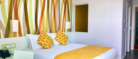 Habitación de hotel con cama, escritorio, teléfono y pared con diseño a rayas.