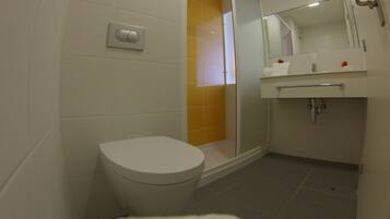 Un baño moderno con inodoro, zona de ducha y lavamanos.