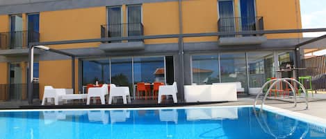Un edificio moderno con piscina, zona de estar exterior y un patio cubierto.