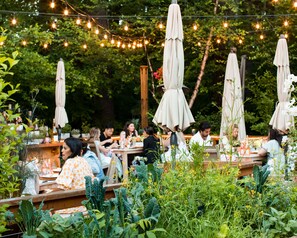 An outdoor dining area with string lights, umbrellas, and lush greenery. - The Inn at Hastings Park, Relais & Chateaux - Boston (Lexington)