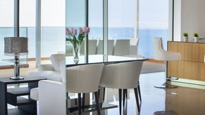 A modern dining area with a glass table, white chairs, and a vase of flowers. - Olympic Residence (Limassol)