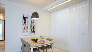 Un comedor moderno con una mesa dispuesta para cuatro, una lámpara colgante y un armario blanco al fondo.