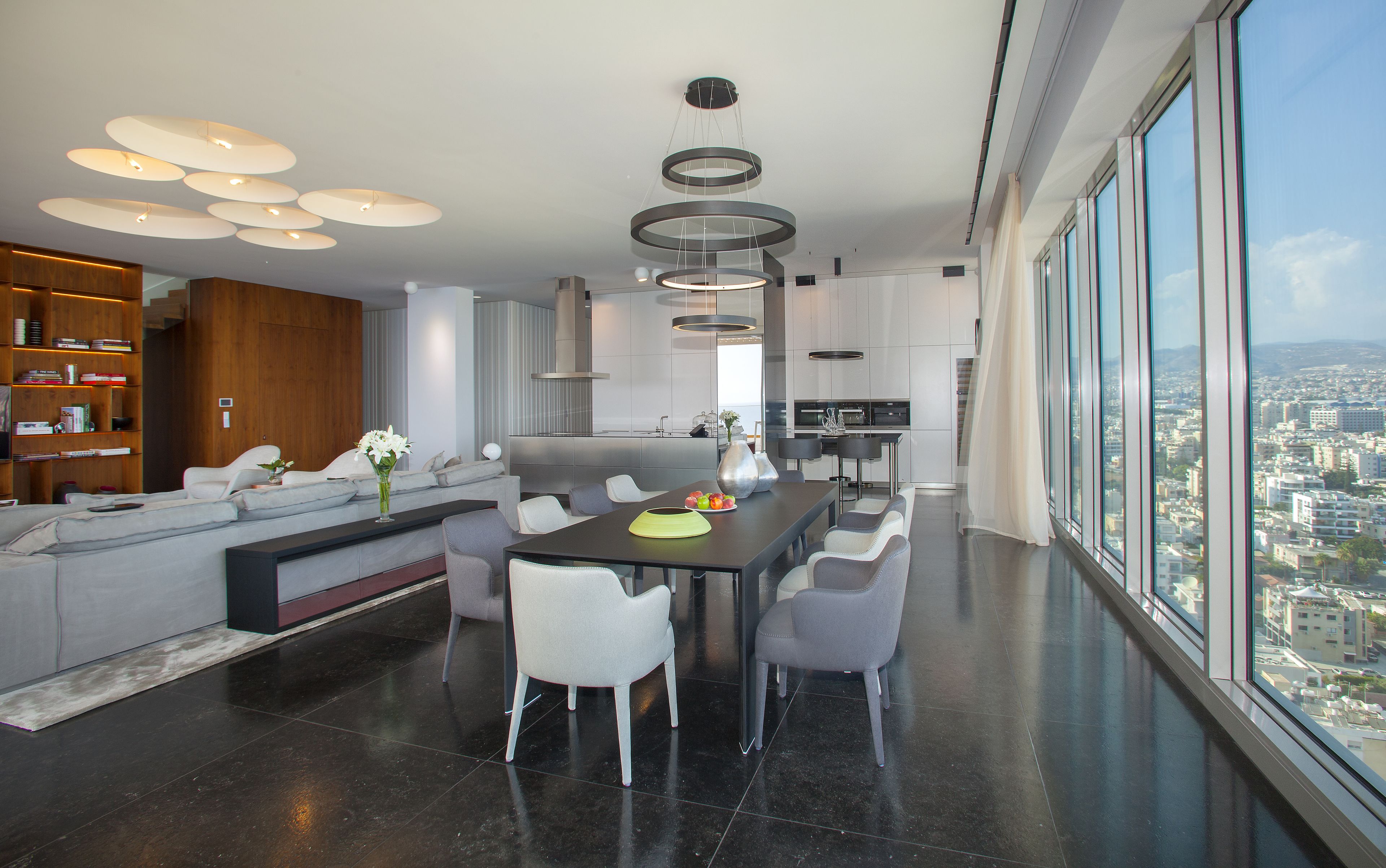 Una sala de estar moderna con comedor, ventanas amplias y vista a la ciudad.